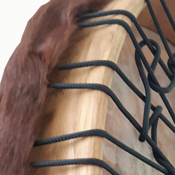 Abbildung: Detailaufnahme des naturfarbigen Eschenholz-Rahmens mit schwarzer Schnurbespannung und überstehendem Fellrand